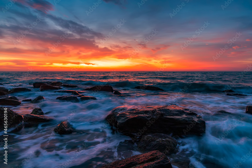 Beautiful motion blur sea waves over the rocks before sunrise