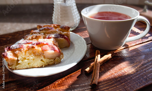 apple pie with cinnamon  served on a wooden tray with aromatic tea and cinnamon sticks