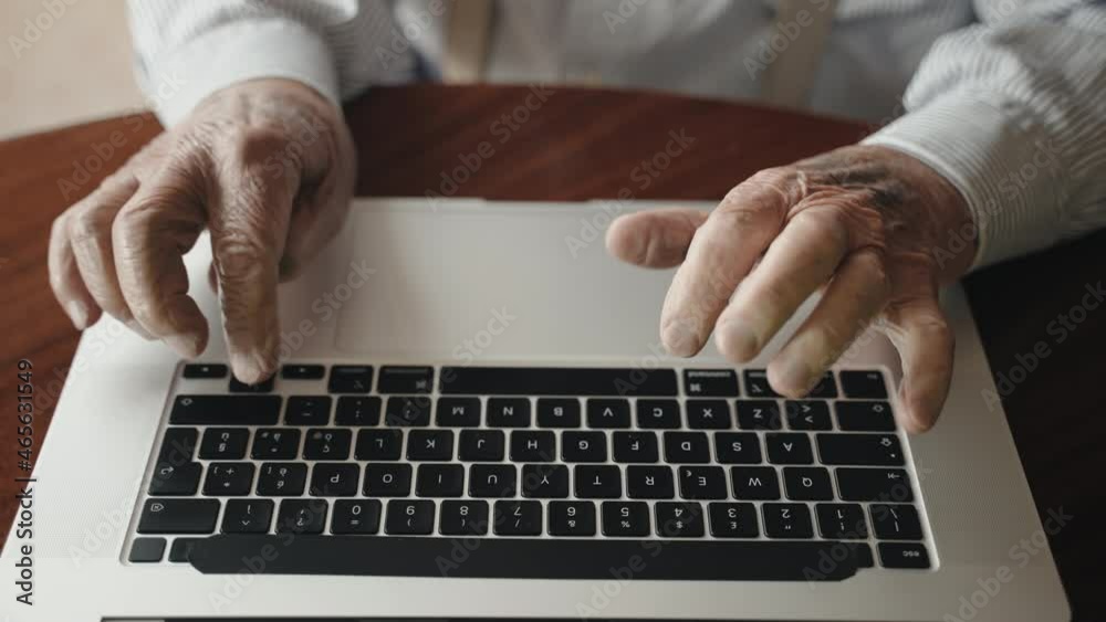 Top view shot of elderly man wrinkled hands typing on trendy computer keyboard, senior male pensioner working at home using modern laptop and online applications. Hands of old man typing on keyboard Top view shot of elderly man wrinkled hands typing on trendy computer keyboard, senior male pensioner working at home using modern laptop and online applications. Hands of old man typing on keyboard