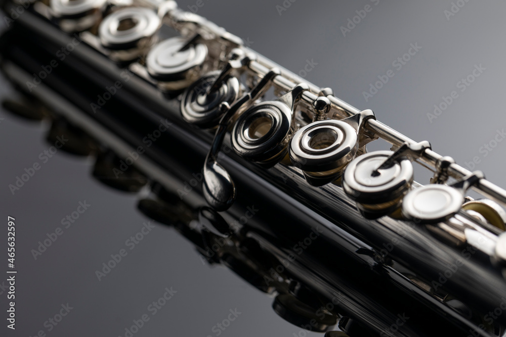 Naklejka premium A silver plated flute with keys on a dark reflective surface
