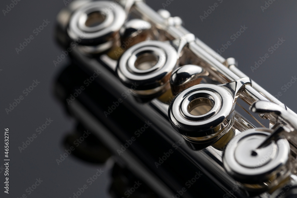 Fototapeta premium A silver plated flute with keys on a dark reflective surface