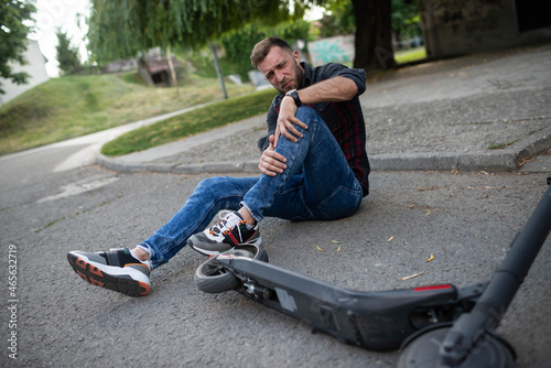 A man who fell from an electric scooter and is holding his knee