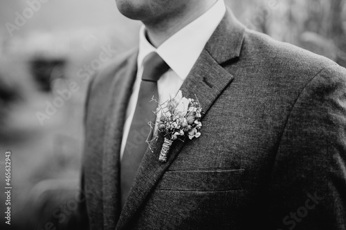 Groom wearing a red tie and boutonniere close up