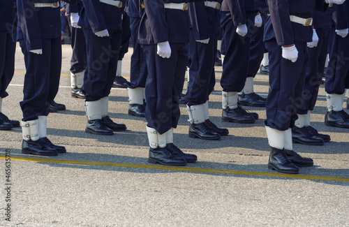 Greek Navy personnel in blue uniform during parade on a public street. Silhouette of Hellenic Armed forces males wearing black boots and white gloves.