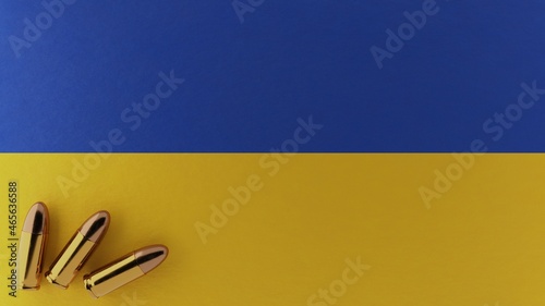 Three 9mm bullets in the bottom left corner on top of the national flag of Ukraine