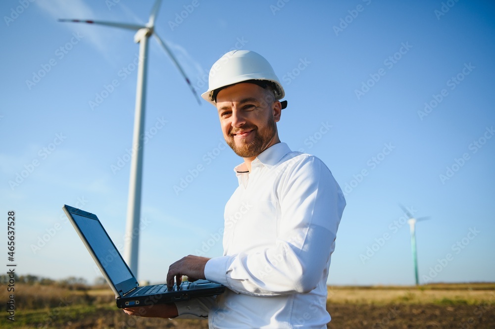 Young engineer man looking and checking wind turbines at field Young engineer man looking and checking wind turbines at field