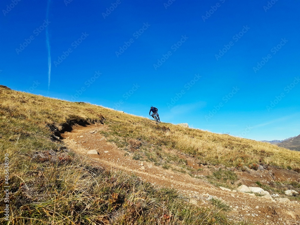 Enduro ride with steep bend, banked curve, Swiss Mountain Alps at Davos Switzerland. With blue clear sky and great view