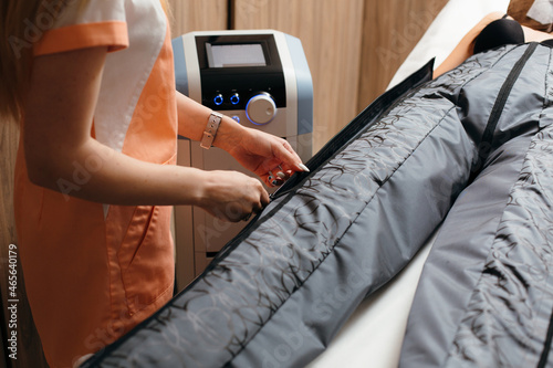 Woman zipping pressotherapy suit for cellulite reduction, getting ready for treatment