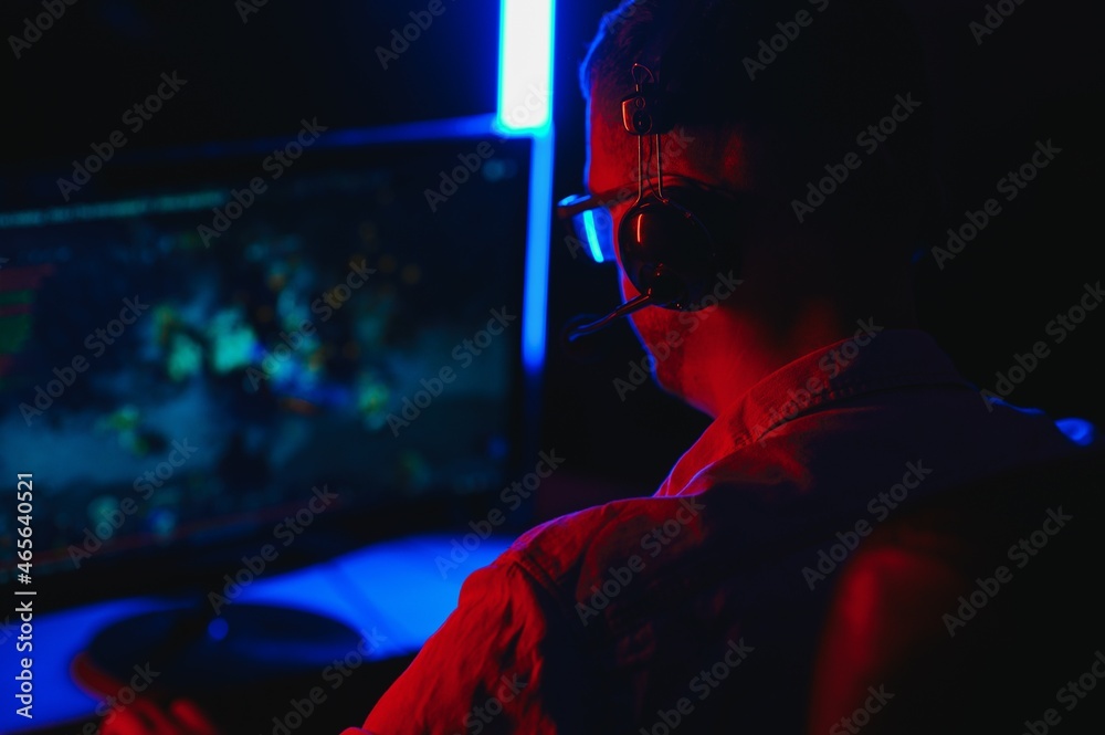 Professional Gamer Plays Video Game on His Computer. He's Participating in Online Cyber Games Tournament or in Internet Cafe. He Wears Glasses and Talks into Microphone. Professional Gamer Plays Video Game on His Computer. He's Participating in Online Cyber Games Tournament or in Internet Cafe. He Wears Glasses and Talks into Microphone.