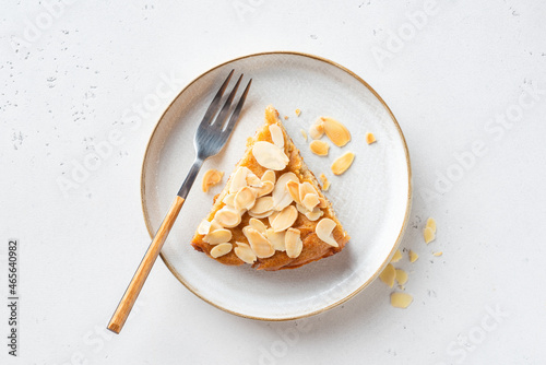 Slice of delicious almond cake on a plate, top view, grey stone background photo