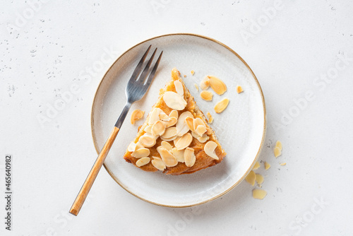 Bild auf Leinwand Slice of delicious almond cake on a plate, top view, grey stone background