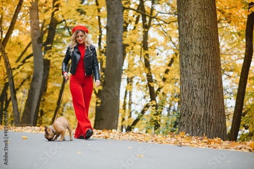Beautiful and happy woman enjoying in park walking with her adorable French bulldog.
