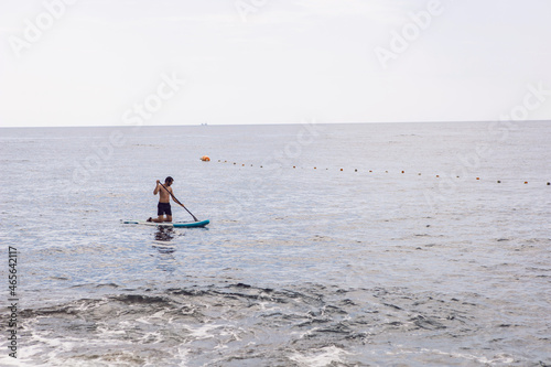 man with a beard swims on stand up paddle board on quiet blue ocean. Sup surfing in water © saulich84