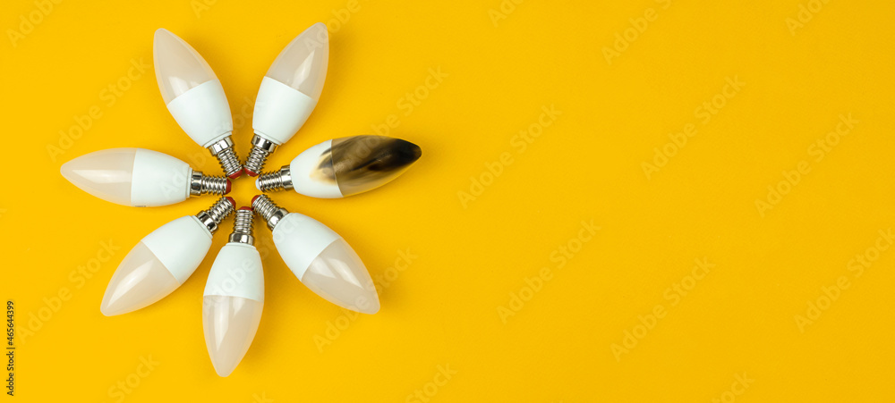 Home safety and electrical short circuit, failure concept. Broken and burn out LED light bulb after fire. Top view, banner with copy space, yellow background