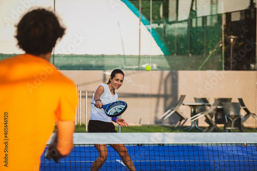 Young teacher is monitoring teaching padel lesson to his student - Coach teaches girl how to play padel on the outdoor tennis court © damianobuffo