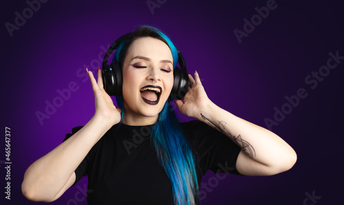 Large banner Woman in black friday, shopping, expressions, with headphones listening to music and dancing, blue hair, copy space, black background, neon style for websites, billboards and boards photo