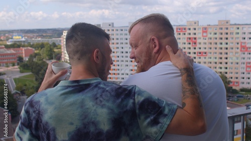 Real life. A loving couple of gays on the balcony greets a new day together, chatting sweetly, drinking tea from a small cup. Discussion of immediate plans. 