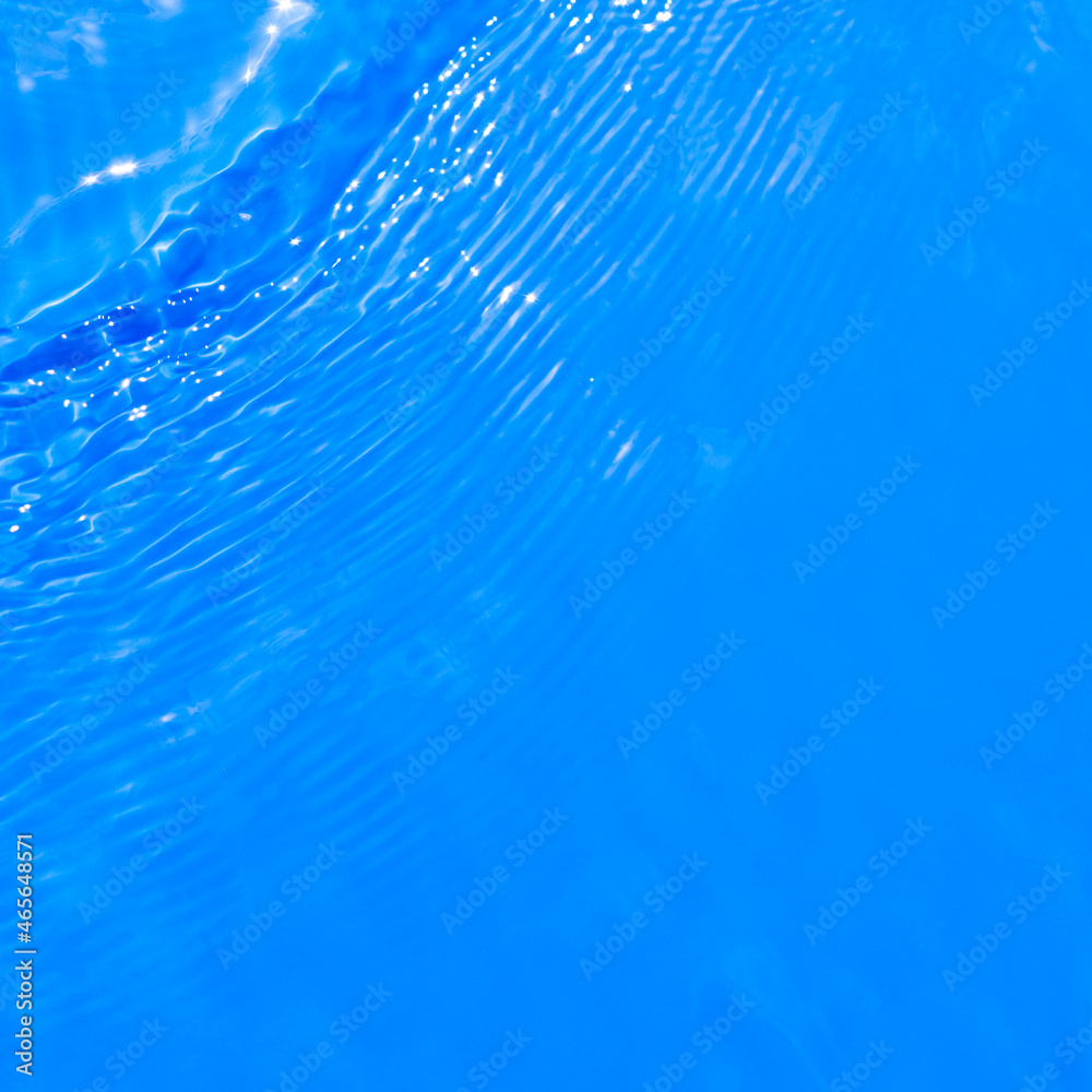 Obraz premium Surface of blue swimming pool water with light reflection. Texture of transparent blue water with ripples and waves in swimming pool. Trendy abstract nature background.