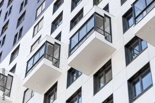 Small balconies on the facade of a modern residential multi-storey building. Viewed from below, close-up. Condominium in a laconic design. Modern apartments