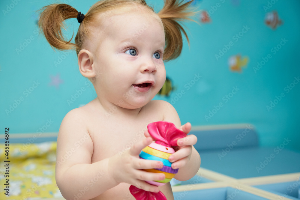 little breastfeeding girl sitting on the changing table with a toy and smiling with two teeth little breastfeeding girl sitting on the changing table with a toy and smiling with two teeth
