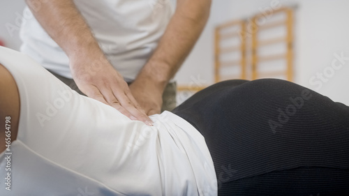 Physiotherapist s hands doing medical back massage  to a female patient  during a rehabilitation treatment.