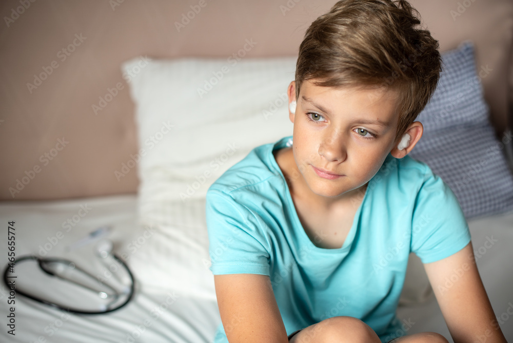 Teen boy suffering from otitis with sterile cotton wool in his ears. Earache, Otitis media, acute ear pain, inflammatory disease of the middle ear Teen boy suffering from otitis with sterile cotton wool in his ears. Earache, Otitis media, acute ear pain, inflammatory disease of the middle ear