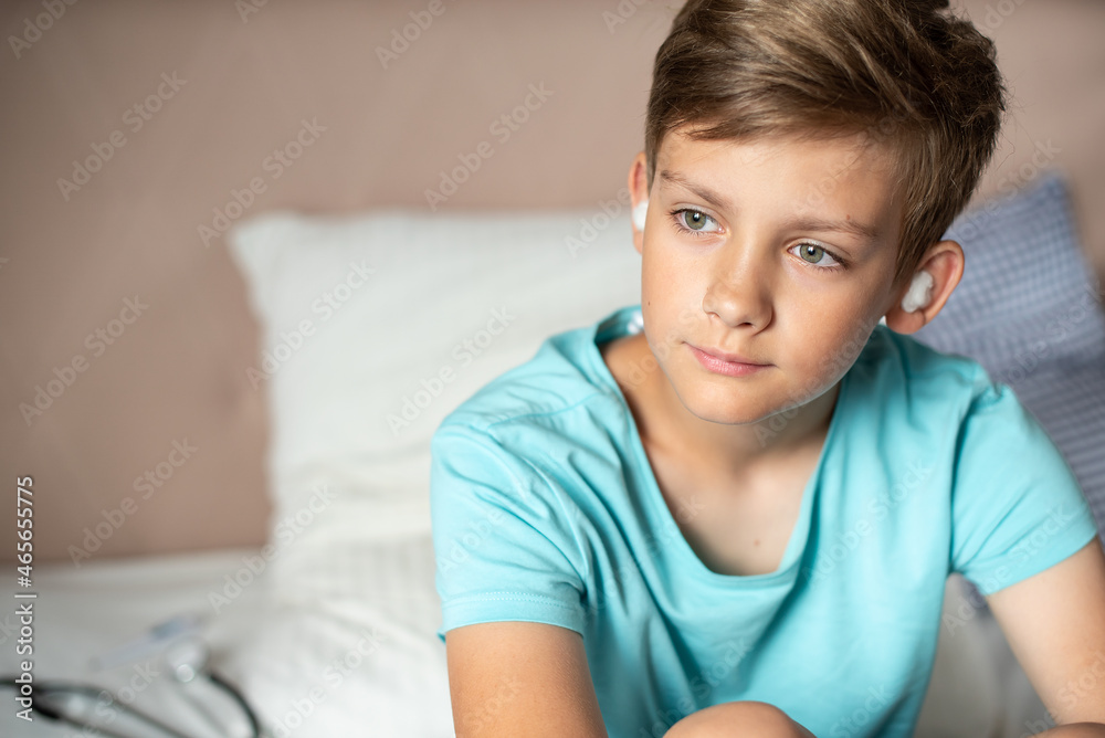 Teen boy suffering from otitis with sterile cotton wool in his ears. Earache, Otitis media, acute ear pain, inflammatory disease of the middle ear Teen boy suffering from otitis with sterile cotton wool in his ears. Earache, Otitis media, acute ear pain, inflammatory disease of the middle ear