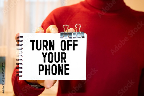 Closeup on businessman holding a card with text TURN OFF YOUR PHONE.