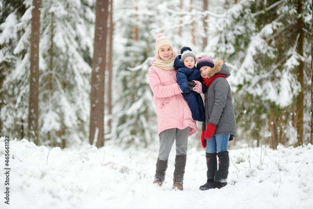Two big sisters and their baby brother having fun outdoors. Two young girls holding their baby boy sibling on winter day. Kids with large age gap.
