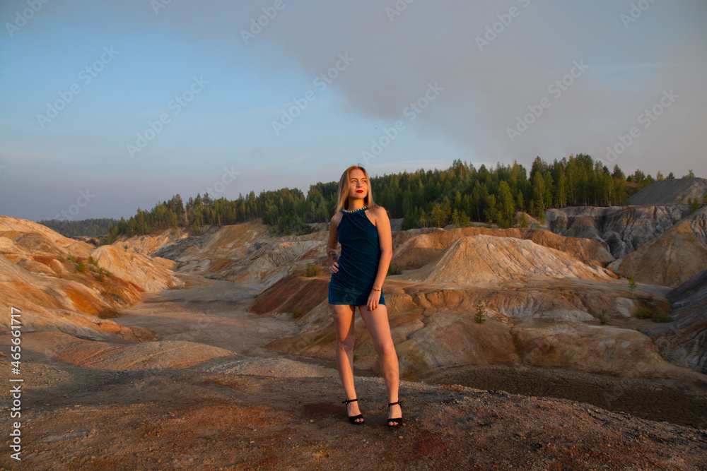 a girl with a tattoo in a blue dress on top of a mountain. quarry and mountains of clay