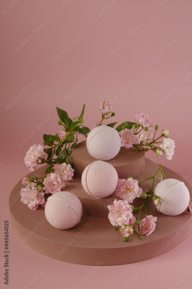 Bath bombs with rose extract.natural cosmetics with rose extract. Beauty and aromatherapy.Flower Bath Bombs. vegan eco cosmetics.Pink bath bombs and pink rose flowers on burgundy pedestal