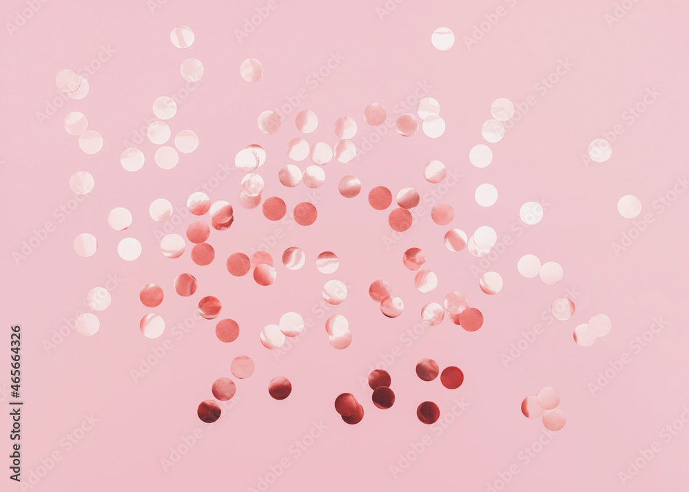 Rose gold confetti. Template for posters and banners. Top view photo. Shiny round confetti on pink background