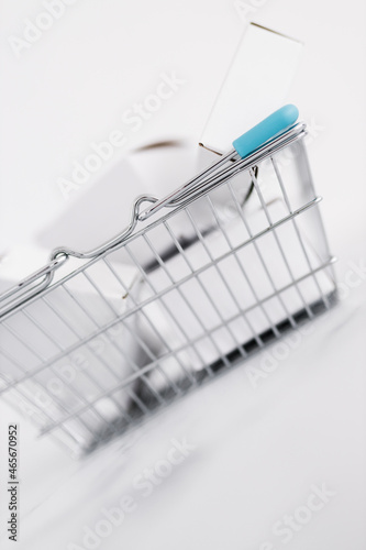 shopping and add to cart concept, parcels of different shapes piled up inside of shopping basket on light marble background