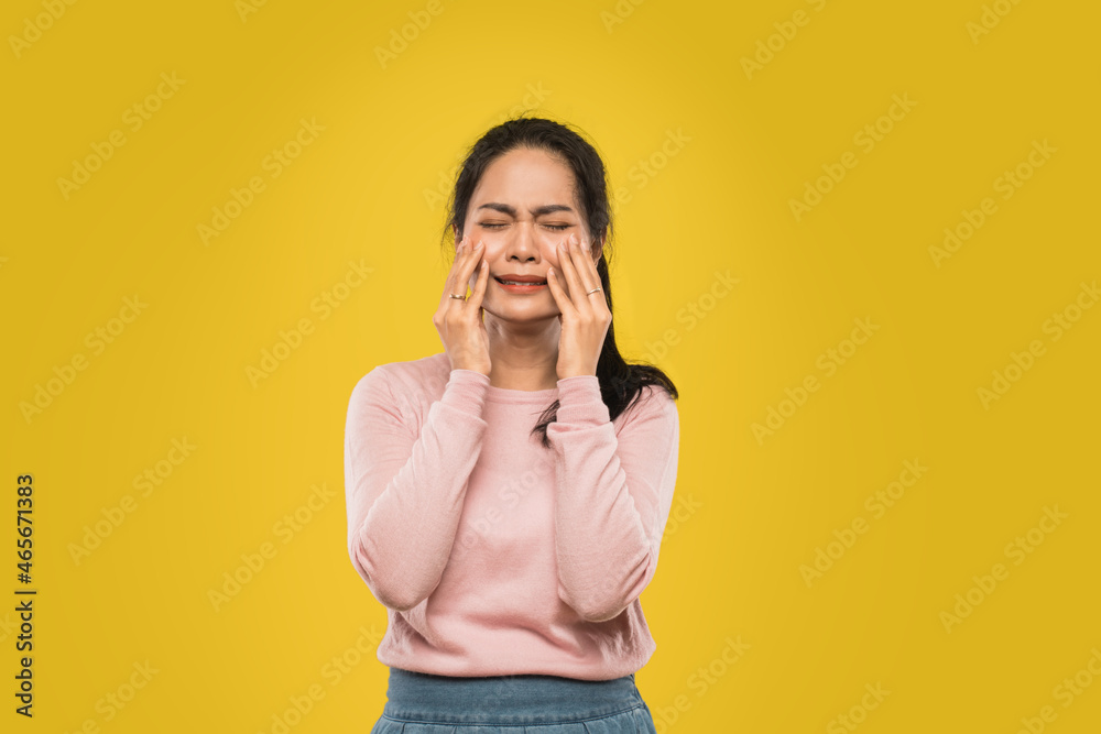 asian woman with hands holding both cheeks while crying with pain expression