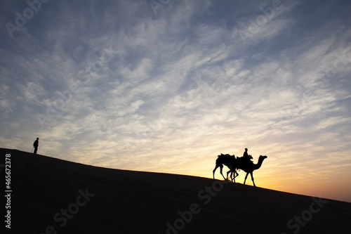 Silhouette of man and his camel at colorful sunset
