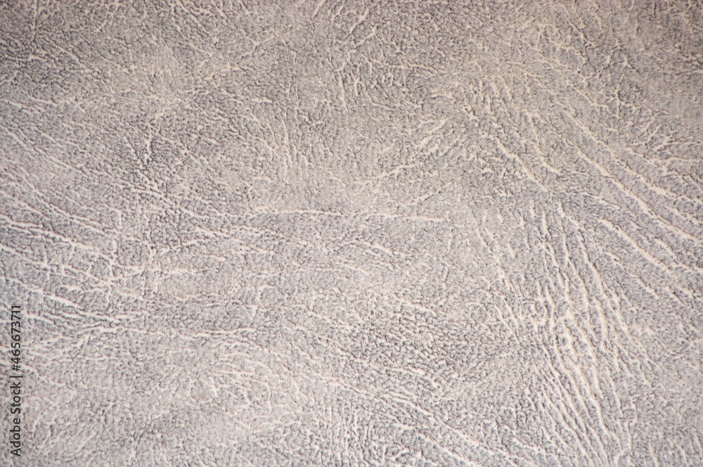 Obraz premium Fragment of light gray natural leather with wrinkles and white folds close-up.
