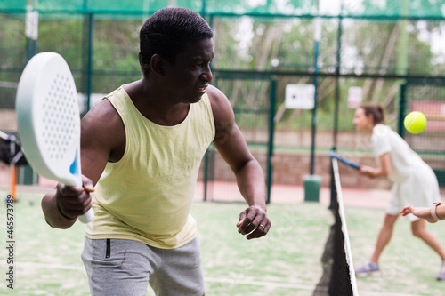 African american man and latino woman playing paddle tennis outdoor