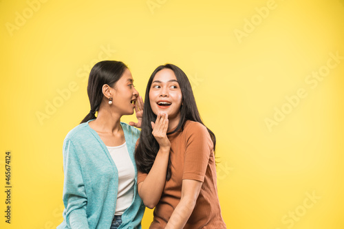 woman surprised when her friend talks whispering in her ear with copyspace photo