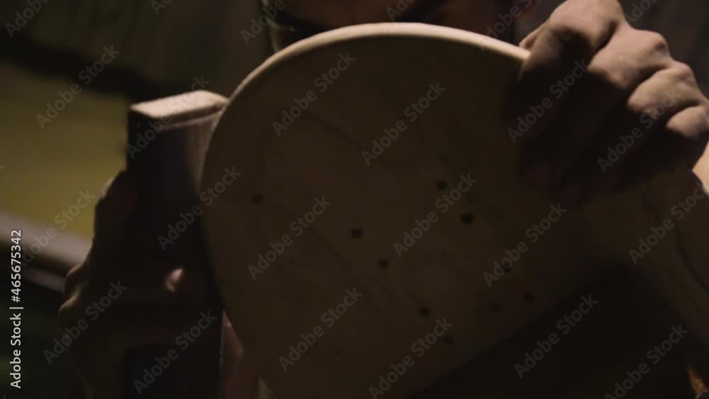 Close up shot of a man polishing surface of wood while making a surfboard. Close up shot of a man polishing surface of wood while making a surfboard.