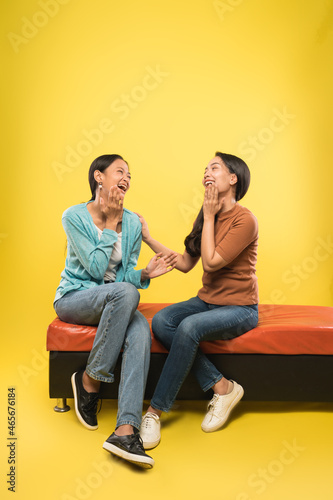 two women laughing happily while chatting sitting relaxed on the sofa