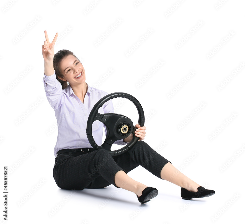 Young businesswoman with steering wheel showing victory gesture on white background Young businesswoman with steering wheel showing victory gesture on white background