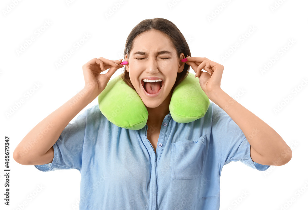 Stressed young woman with travel pillow and earplugs on white background Stressed young woman with travel pillow and earplugs on white background