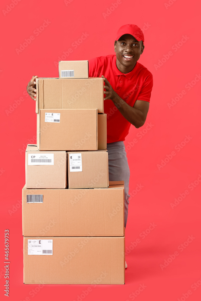 African-American delivery man with many parcels on color background African-American delivery man with many parcels on color background
