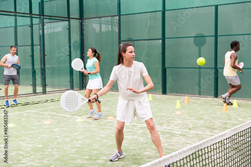 Sportive woman playing padel. In the background, athletes are training © JackF