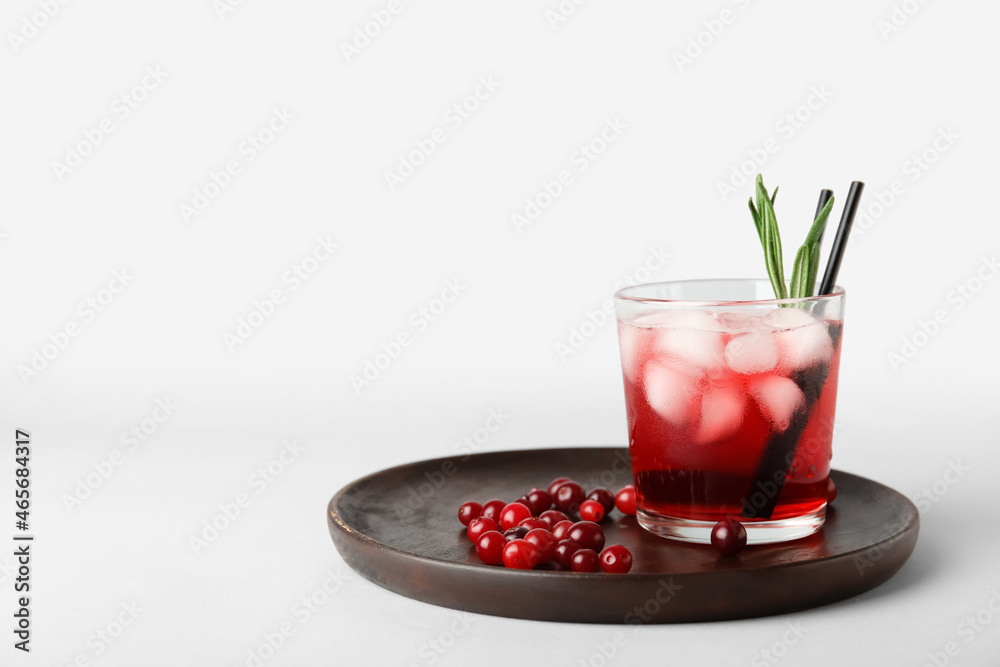 Glass with healthy cranberry juice on light background