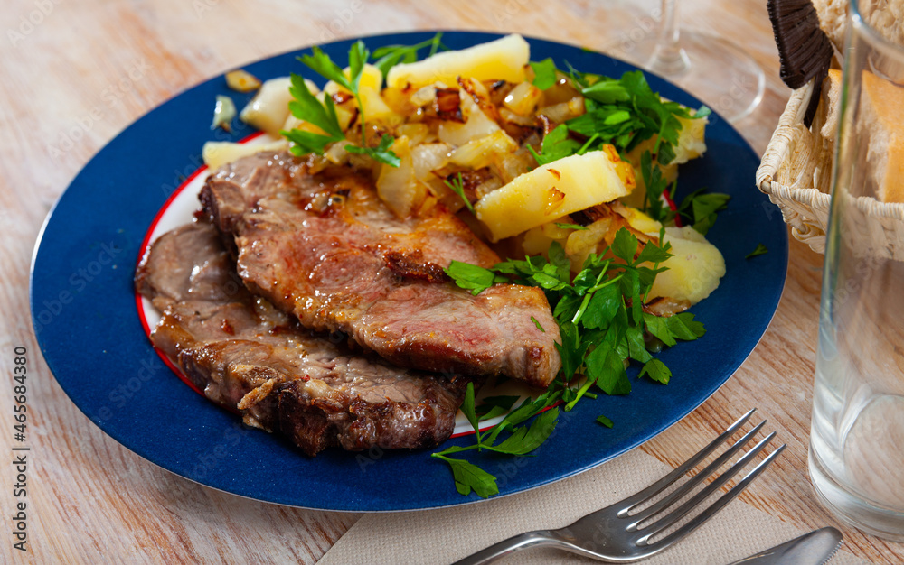 Tasty steaks of pork loin served with homestyle boiled potatoes, fried chopped onion and greens