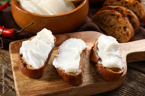Pieces of bread with lard spread on wooden background