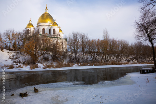 Scenic winter landscape overlooking majestic building of Trinity Cathedral with golden domes on bank of Tsna river in Russian town of Morshansk