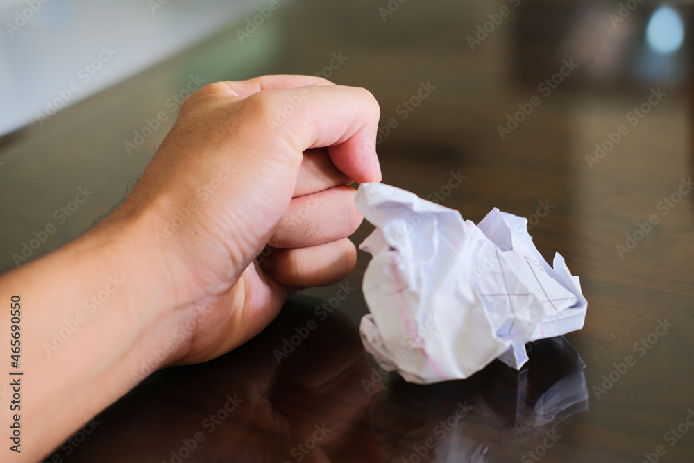 Fototapeta premium Person hand clenched beside crushed paper work. Angry concept