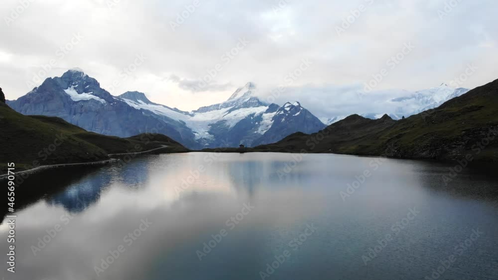 Aerial flyover over lake Bachalpsee in Grindelwald First, Switzerland with a view of Schreckhorn and other Bernese Oberland peaks in the reflection